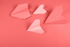 珊瑚粉红色的纸飞机彩色的背景
