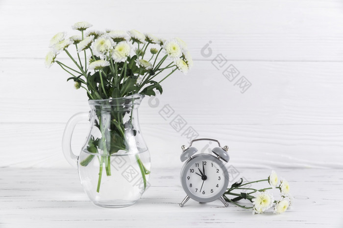 菊花白色花玻璃Jar附近小报警时钟木桌子上