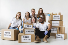笑脸志愿者摆姿势在一起与捐赠盒子与食物