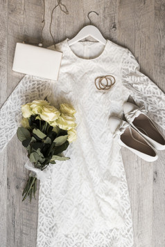 新娘婚礼衣服与鞋子离合器丢玫瑰花束系与白色丝带木背景