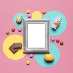 空框架包围与复活节鸡蛋兔子糖果巧克力块粉红色的背景