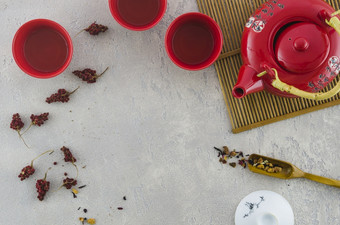 红色的亚洲杯茶壶与草本植物变形灰色背景