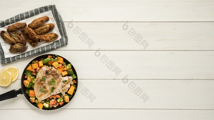 菜与鸡翅膀煎锅蔬菜木桌子上