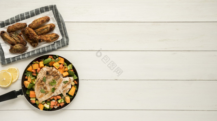 菜与鸡翅膀煎锅蔬菜木桌子上图片