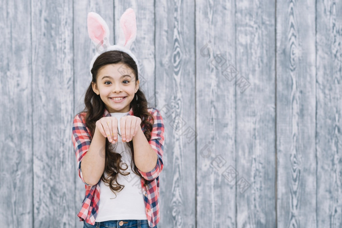 微笑女孩与兔子耳朵摆姿势就像兔子对灰色的木桌子上