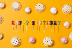色彩斑斓的快乐生日蜡烛装饰与阿劳波尔卡点纸蛋糕形式黄色的背景