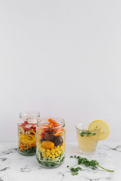 沙拉蔬菜两个梅森Jar与玻璃柠檬汁大理石前