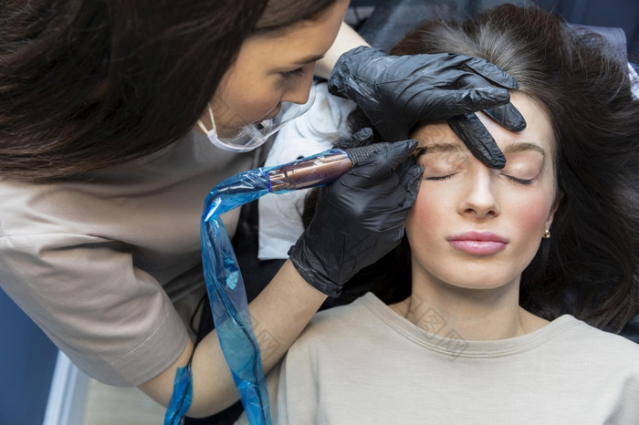 美容师做眉治疗她的客户端美容师做眉治疗她的客户端