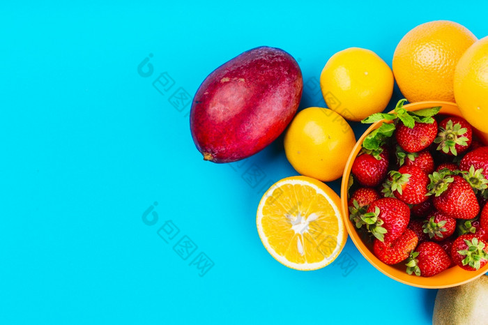 芒果橙子碗草莓蓝色的背景
