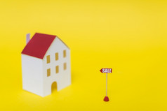 出售标签前面模糊房子模型对黄色的背景