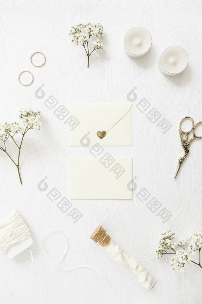 两个信封包围与婚礼环蜡烛剪刀字符串测试管婴儿呼吸花白色背景