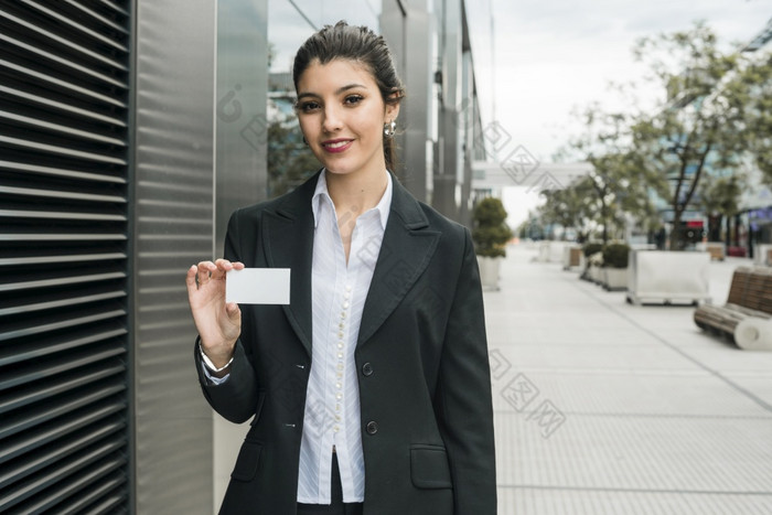 快乐年轻的女商人站外办公室建筑显示她的业务卡