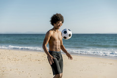 微笑年轻的非洲美国男人。玩足球海岸