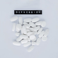 各种各样的白色药片与抑郁症标签灰色背景