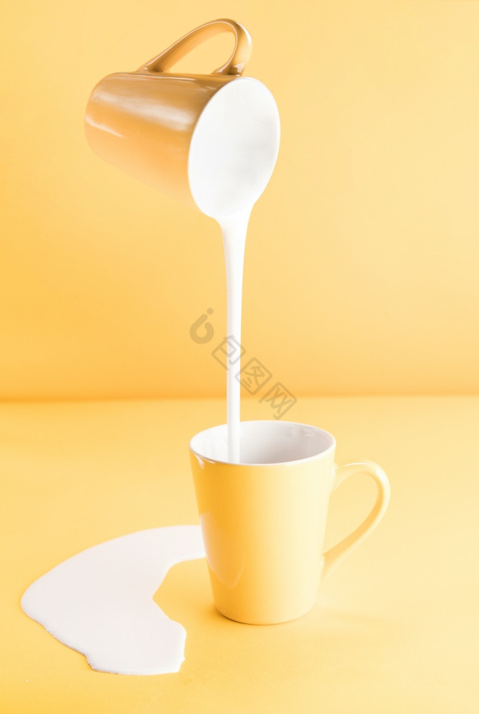 杯子倒牛奶成另一个杯子图片