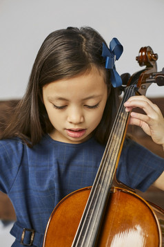 年轻的可爱的女孩学习如何玩大提琴