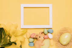 空白色边境框架装饰与莉莉花兔子小雕像复活节鸡蛋黄色的背景