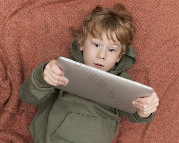 前视图年轻的男孩使用平板电脑床上