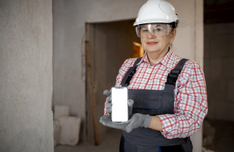 女建设工人与头盔持有智能手机