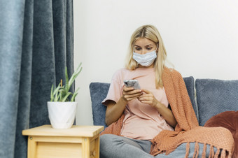 女人与医疗面具智能手机首页在流感大流行