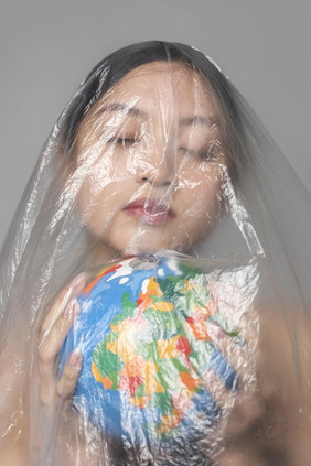 年轻的女人持有地球全球而被覆盖塑料