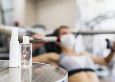 散焦女人健身房使用设备与医疗面具手洗手液瓶