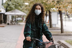女人穿医疗面具骑自行车前面视图