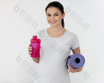 前面视图怀孕了女人持有健身席瓶水
