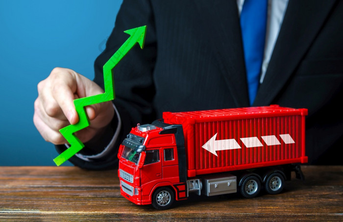 商人持有绿色箭头和卡车生产增长进口出口结束容器短缺危机运输通货膨胀高航运利率定价上升增加交通