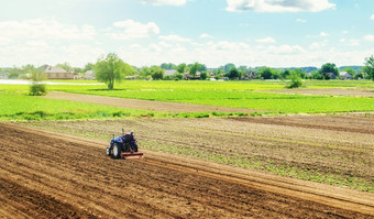 农民拖拉机与铣机放松磨和混合地面培养土地土壤为进一步种植放松改善土壤质量食物生产蔬菜种植园