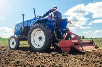 农民拖拉机与铣机流程放松土壤的农场场准备为新作物种植磨和混合土壤种植园放松表面培养的土地