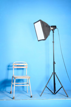 可移植的工作室闪光与softbox而且老椅子在的蓝色的背景