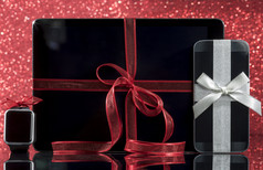 智能手机和智能手表和平板电脑和装饰为圣诞节树黑色的玻璃表格在红色的背景焦点智能手机