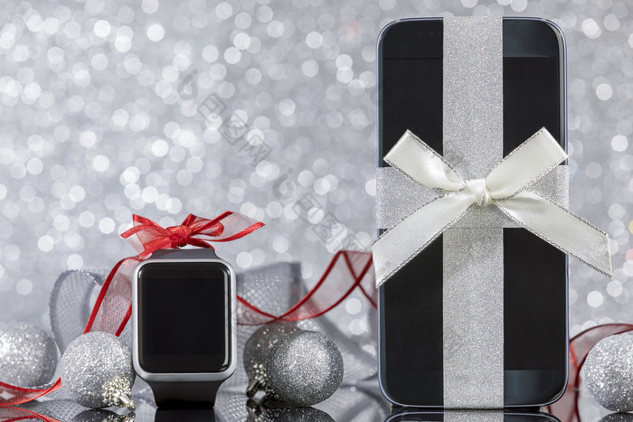 智能手机和智能手表和装饰为圣诞节树黑色的玻璃表格焦点智能手机