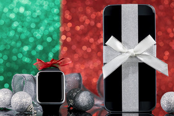 <strong>智能手机</strong>和<strong>智能手表</strong>和装饰为圣诞节树黑色的玻璃表格在绿色和红色的背景焦点<strong>智能手机</strong>