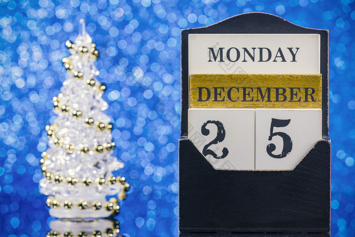 木日历和圣诞节树反射玻璃表格在蓝色的背景
