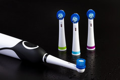 电可充电牙刷与三个牙刷头黑色的背景与水滴焦点的权力按钮