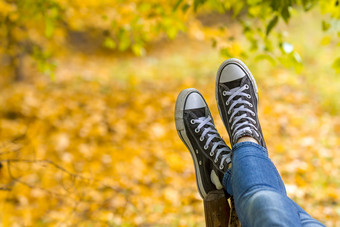 放松十几岁的女孩穿运动鞋说谎板凳上秋天公园特写镜头焦点运动鞋