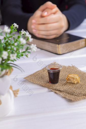 年轻的女人祈祷和采取交流的酒和的面包符号耶稣基督血和身体与神圣的圣经复活节逾越节和主晚餐概念焦点玻璃
