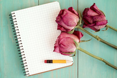 老玫瑰和空白笔记本在木表格前视图与复制空间