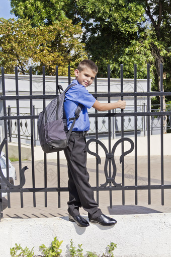 可爱的男孩是挂的栅栏与学校背包男孩挂的栅栏与学校背包