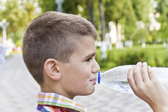 可爱的男孩是喝水从瓶可爱的浅黑肤色的女人男孩11年老