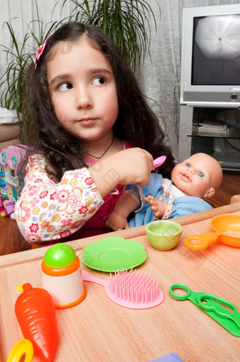 小女孩玩在室内喂养她的娃娃小女孩玩与娃娃