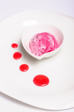 树莓分层奶酪蛋糕和粉红色的冰奶油球孤立的白色