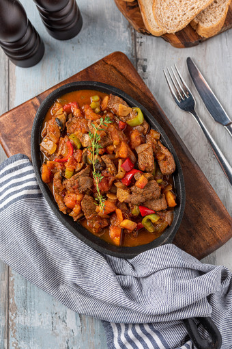 牛肉炖肉与土豆胡萝卜和草本植物铁砂锅前视图美味的牛肉炖肉