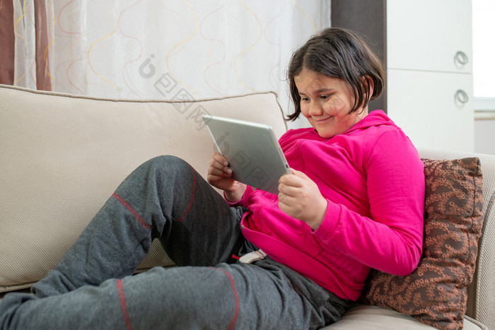 微笑女孩坐着的沙发的生活房间研究首页因为科维德冠状病毒检疫和距离学习概念距离学习概念