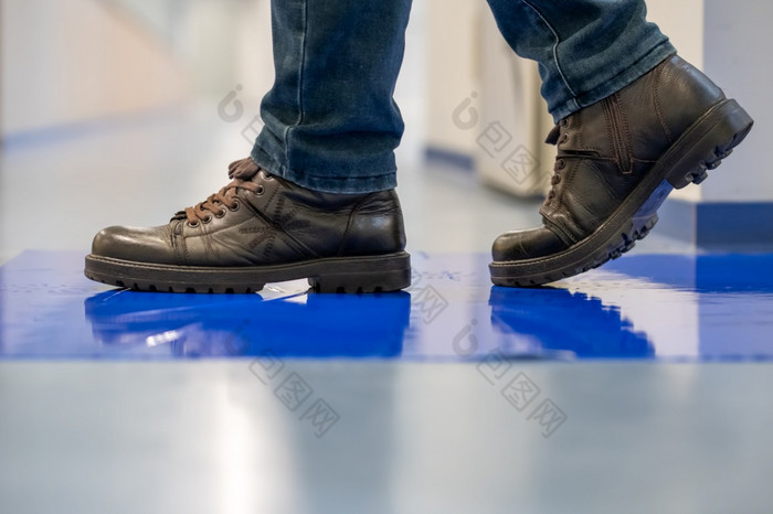 男人。棕色（的）鞋子步进蓝色的胶粘剂黏糊糊的垫