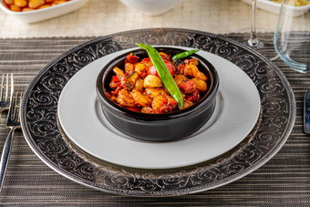 虾炖肉与西红柿大蒜和辣椒黑色的石头碗