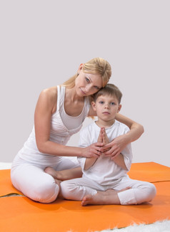 美丽的年轻的妈妈。实践瑜伽与她的儿子