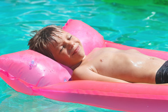 微笑男孩谎言粉红色的床垫的池